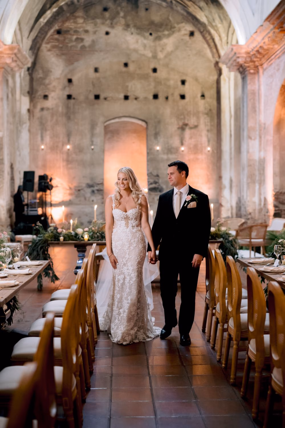 Bride and groom walk down the central aisle of the reception inside the ruined nave of San José el Viejo.