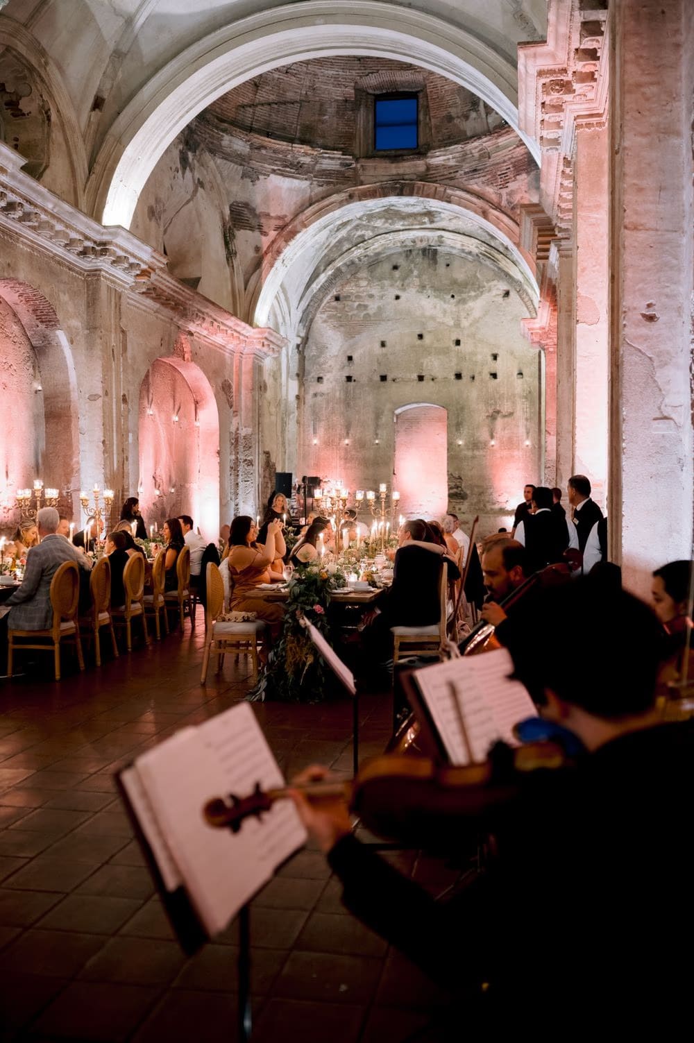 String quartet plays in the foreground as guests dine beneath the vaulted ruins of San José el Viejo.