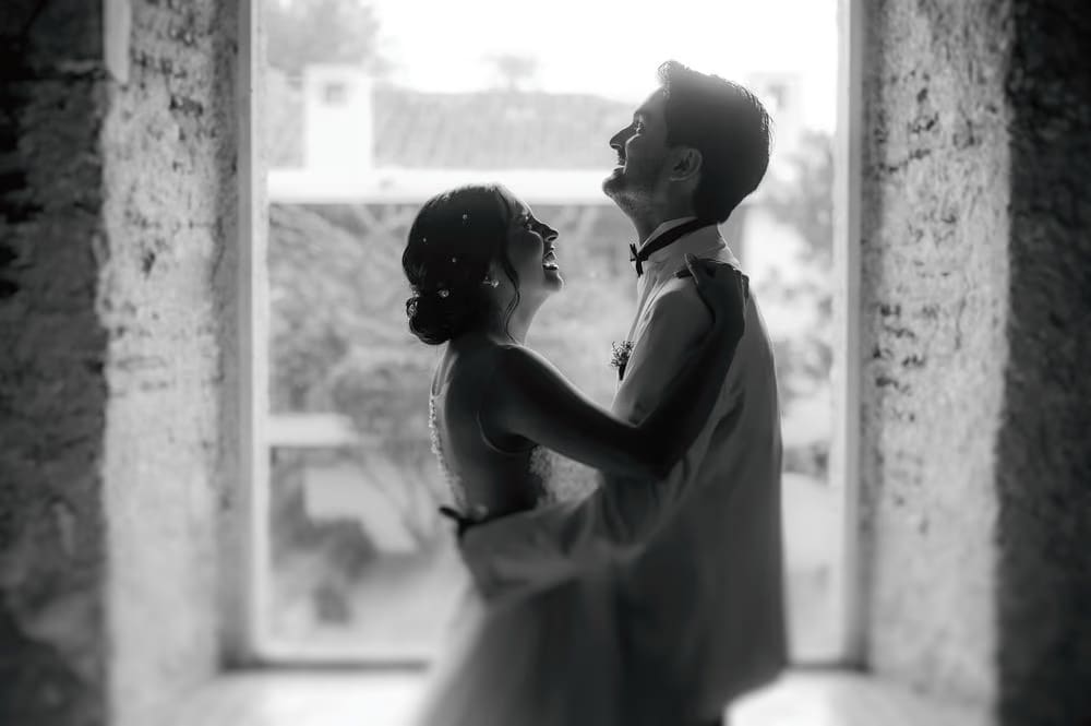 Black-and-white portrait of the couple framed by a stone window at Hotel Casa Santo Domingo, Antigua Guatemala.