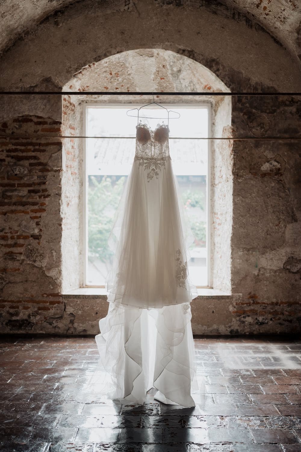 Wedding dress hanging in a candle-lit vaulted brick chamber at Casa Santo Domingo — destination wedding in Antigua Guatemala.