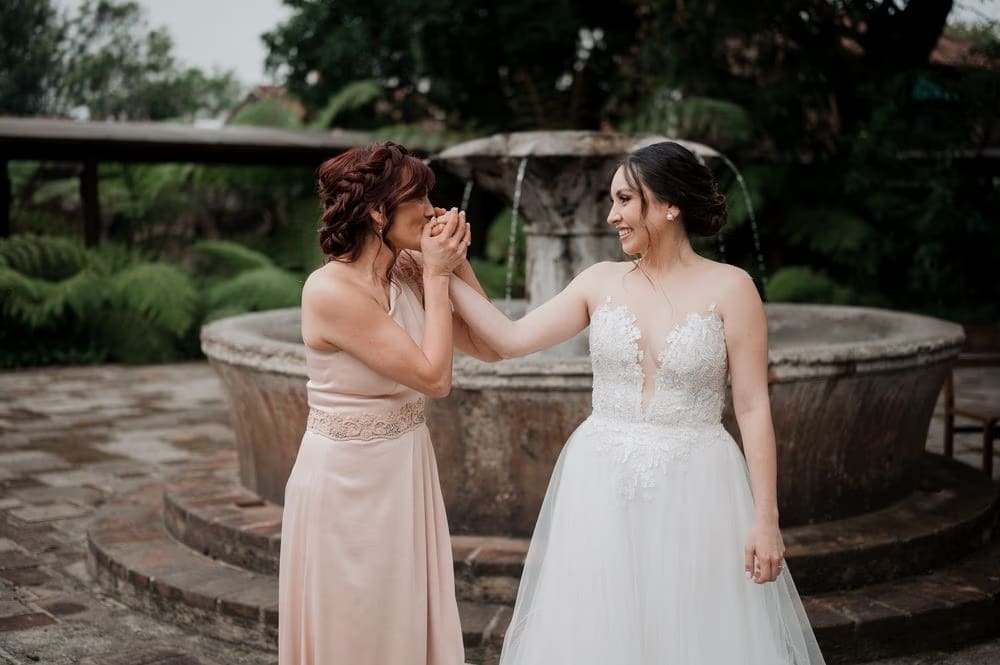 Tender moment between the bride and a bridesmaid at the colonial fountain courtyard — wedding in Antigua Guatemala.