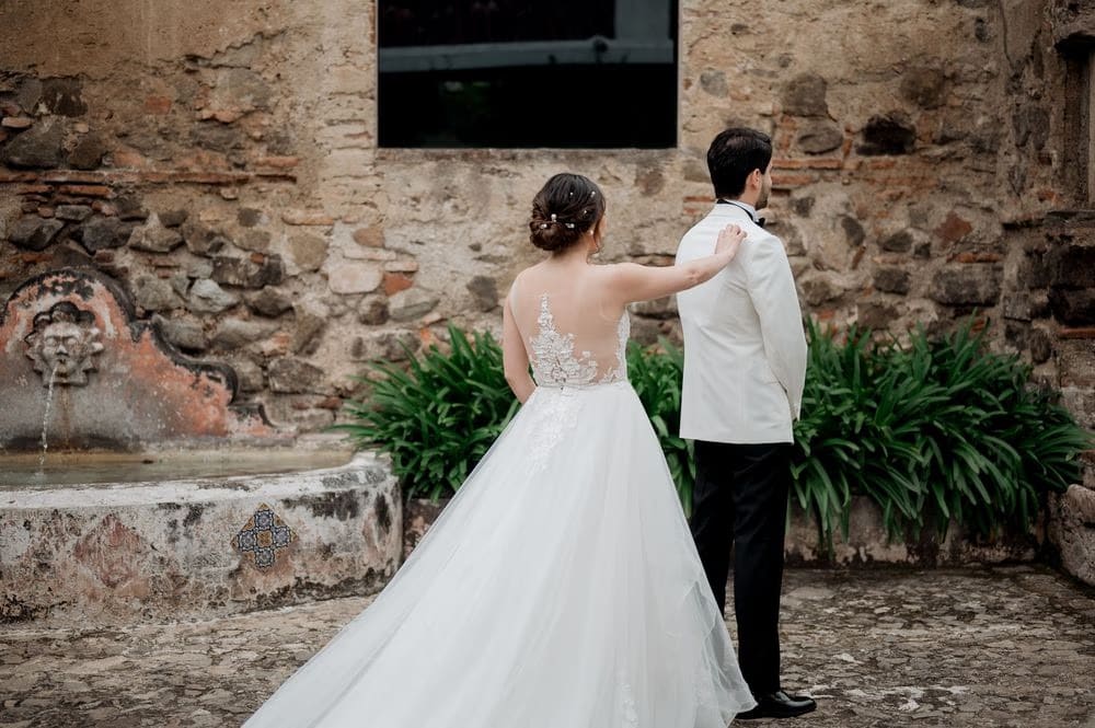 Couple from behind beside a tiled stone fountain wall at the colonial monastery in Antigua Guatemala.