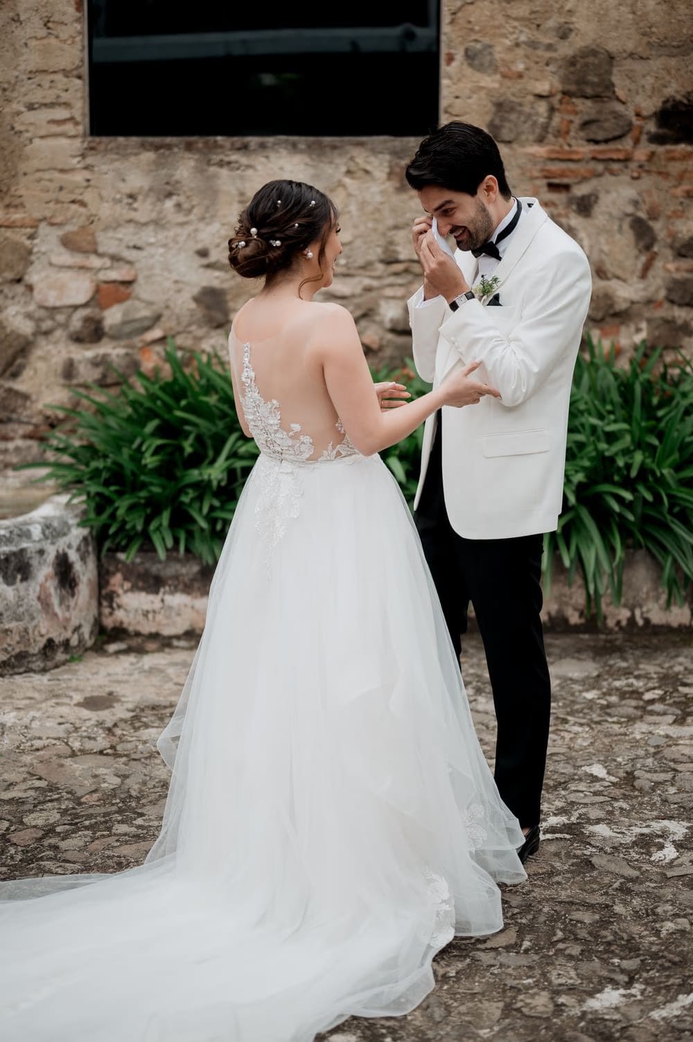 Groom wipes away a tear during the first look as the bride steadies his arm at Hotel Casa Santo Domingo, Antigua Guatemala.