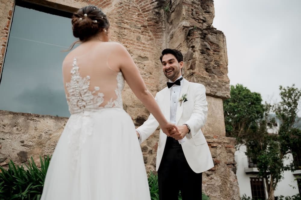 Groom smiles widely as the bride faces him in front of colonial ruins at Casa Santo Domingo.