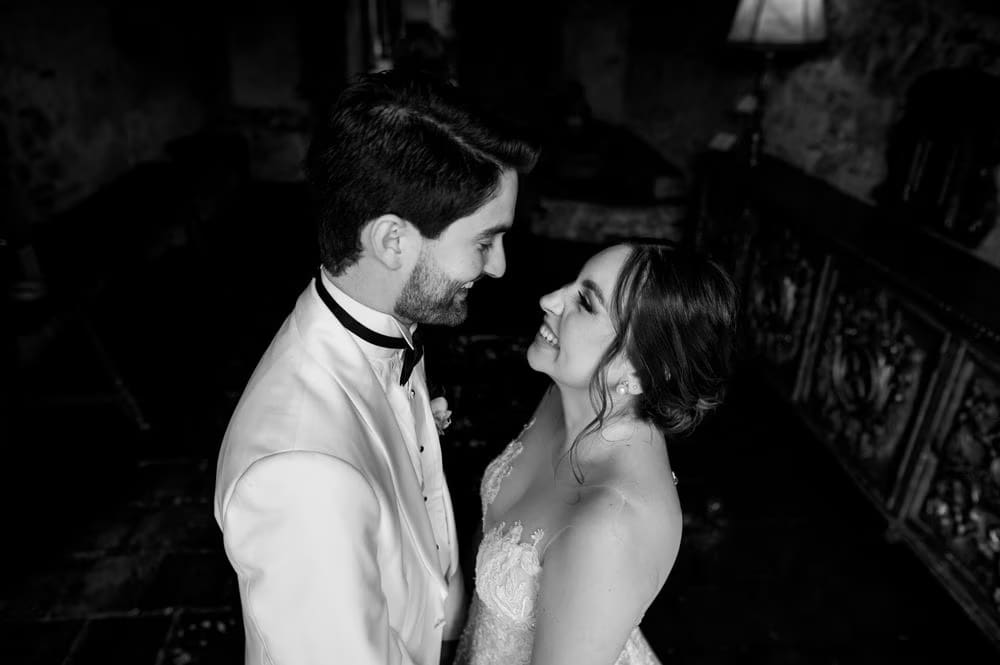 Black-and-white close-up of the couple laughing inside a candle-lit corner at Casa Santo Domingo.