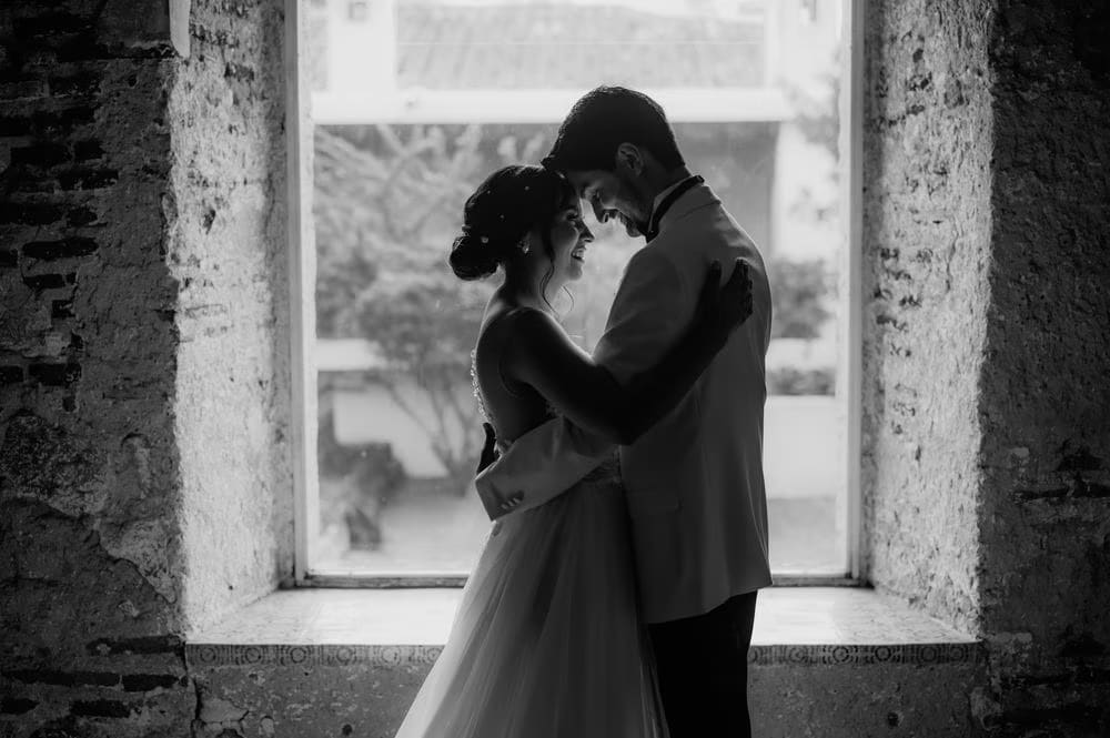 Black-and-white silhouette of the couple framed by a stone window inside Hotel Casa Santo Domingo.
