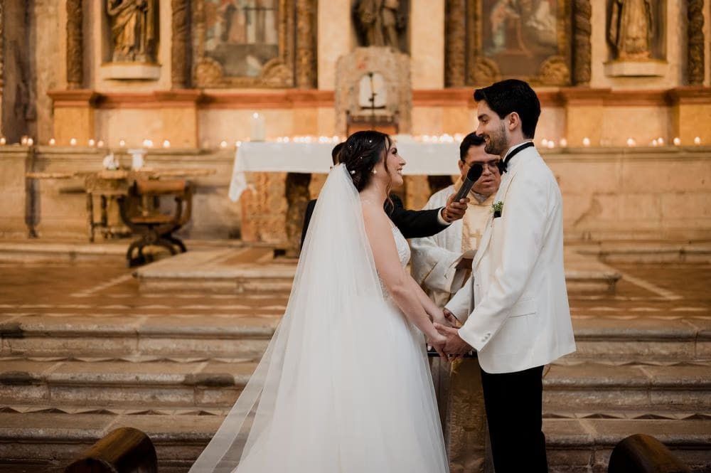 Couple holds hands before the gilded baroque altar during their wedding ceremony at Casa Santo Domingo.