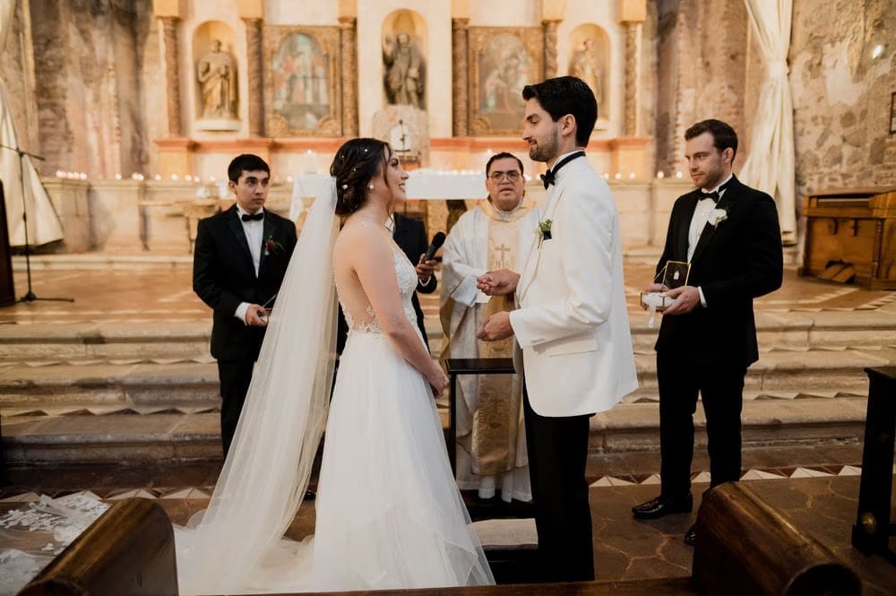 Bride and groom face the celebrant with cathedral veil flowing during their ceremony in Antigua Guatemala.