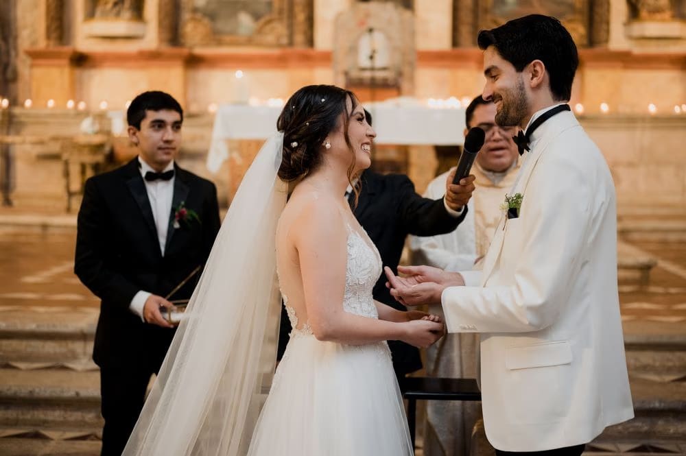 Couple exchange vows at the microphone in the candle-lit monastery church at Hotel Casa Santo Domingo.
