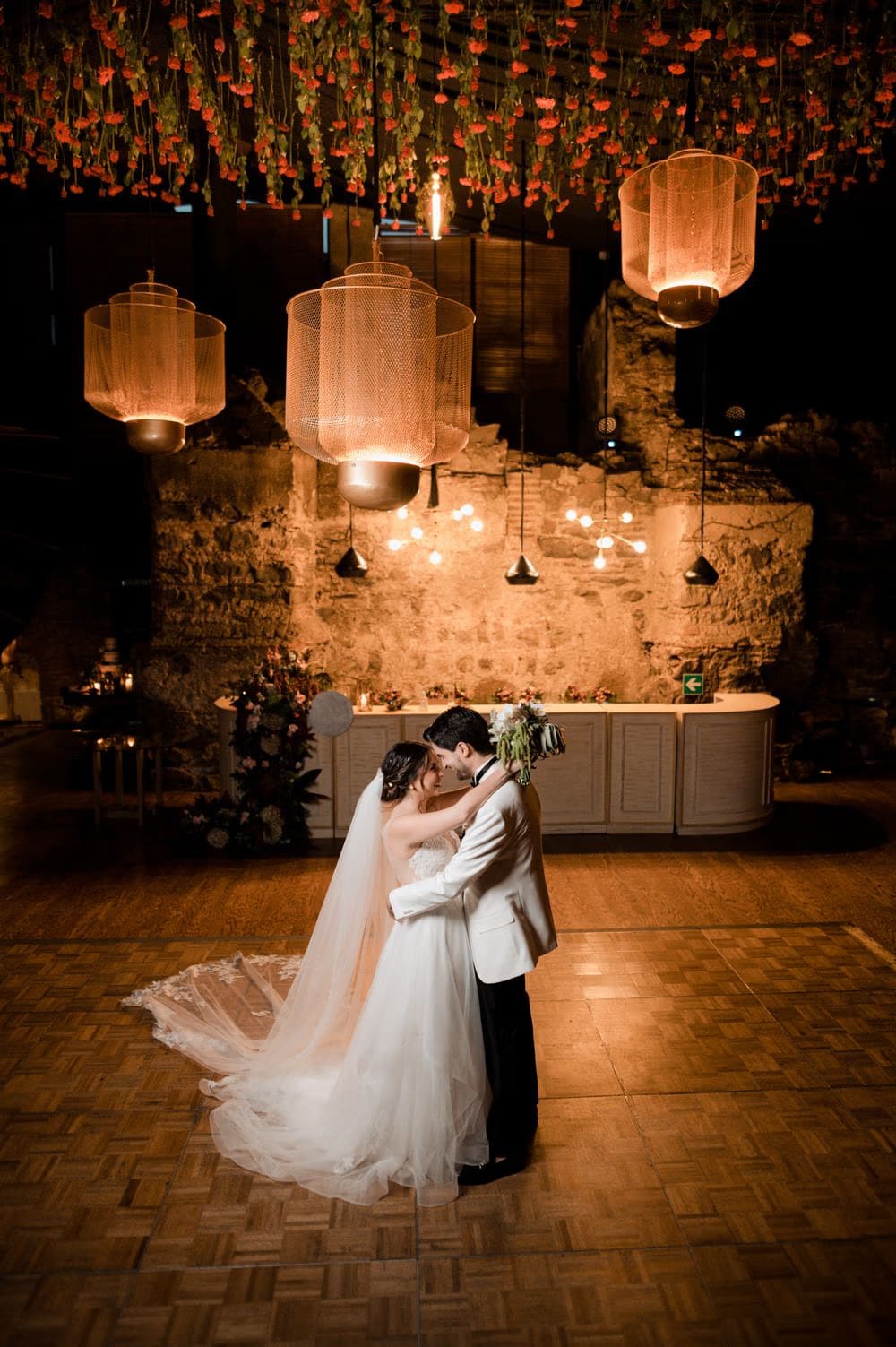 Vera and Ernesto kiss on the parquet dance floor beneath a hanging carnation ceiling and woven lanterns at Hotel Casa Santo Domingo.