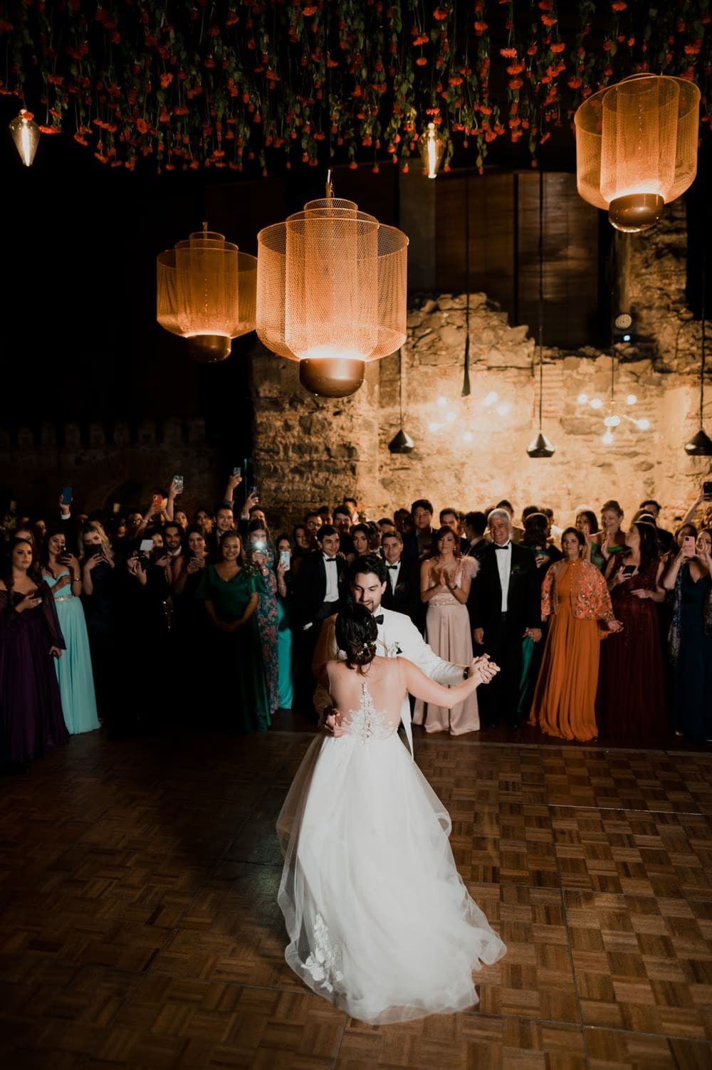 Couple's first dance circled by guests filming on phones beneath the carnation ceiling — destination wedding in Antigua Guatemala.